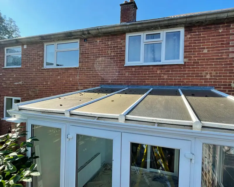 Discoloured lean-to conservatory roof on a red brick semi