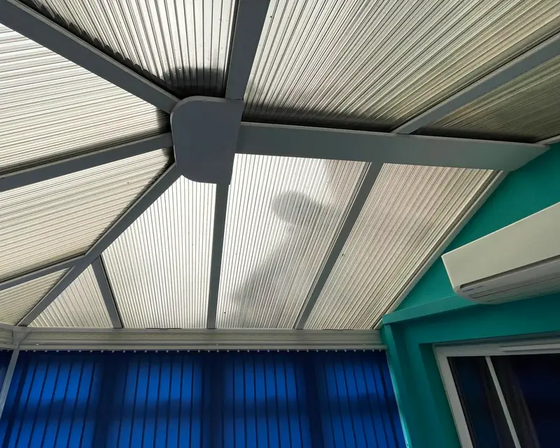 Ribbed polycarbonate roof over a conservatory with teal walls