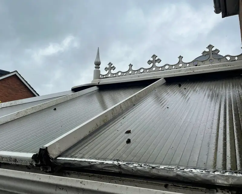 Weathered polycarbonate roof below a decorative ridge cresting