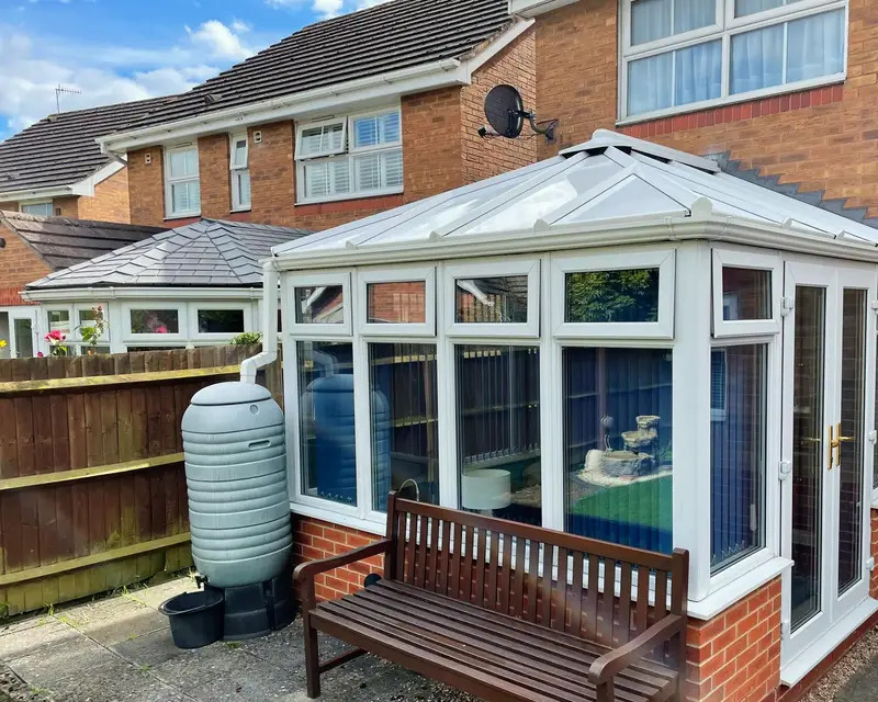 Victorian conservatory with white panel roof and a garden bench