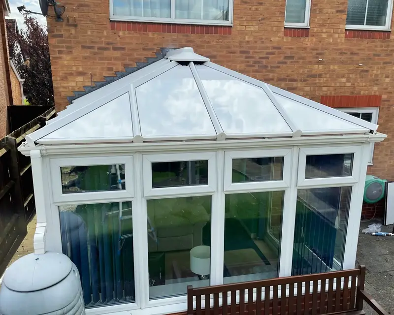 Hipped conservatory with a new white insulated panel roof, front view