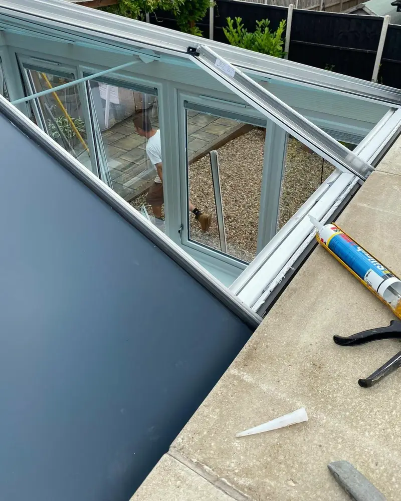 Sealant being run along the edge of a grey roof panel